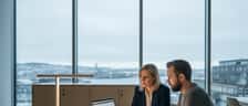 Finansrådgiver i konsultasjon med klient på et moderne kontor i Oslo med dokumenter og porteføljedata på skrivebordet