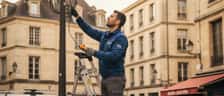 Mann steht in deutschem Wohnungsflur und schaut auf sein Smartphone vor offenem Sicherungskasten