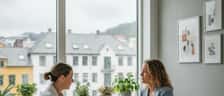 Ernæringsfysiolog i konsultasjon med klient ved et lyst kontorpult i en moderne norsk klinikk