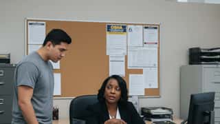 Two employment law professionals reviewing Missouri labor law documents at a union hall table in St. Louis, warm tungsten light, forest green legal binders