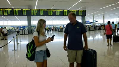 Australian travellers at Fiji airport checking cancelled flight notices during Cyclone Vaianu