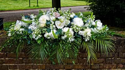 Weiße Trauerblumen auf einem Friedhof als Symbol für einen Todesfall