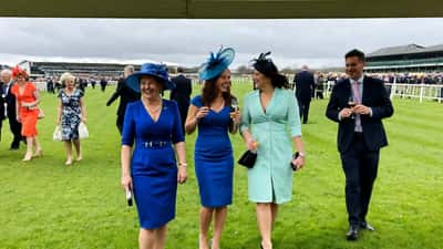 Elegantly dressed women in bold spring dresses and statement hats at Aintree racecourse Ladies Day