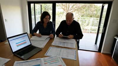 Australian couple reviewing mortgage documents and RBA interest rate decision materials at home