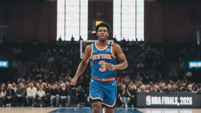 Basketball player in a New York Knicks jersey sprinting on an NBA court during the 2026 Finals