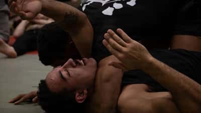 MMA fighters training in a combat sports clinic, demonstrating grappling techniques
