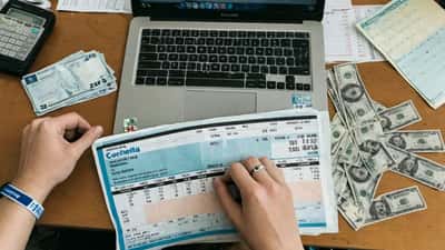 Canadian woman at desk comparing Coachella ticket prices on laptop with budget spreadsheet and Canadian dollars