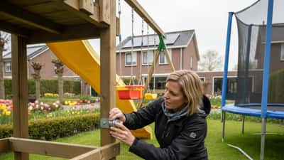 Nederlandse ouder die een houten klimrek in de achtertuin inspecteert op veiligheid