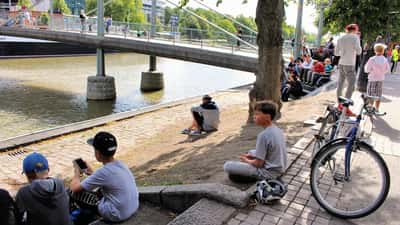 Pessoas jogando Pokémon GO em parque, segurando smartphones durante caça de Pokémons