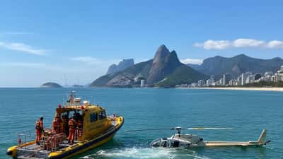 Barco de resgate do Corpo de Bombeiros próximo a helicóptero nas águas da Barra da Tijuca, Rio de Janeiro