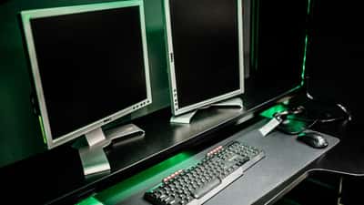 Gaming-Setup mit Dual-Monitor, Tastatur und Maus in einem abgedunkelten Spielzimmer