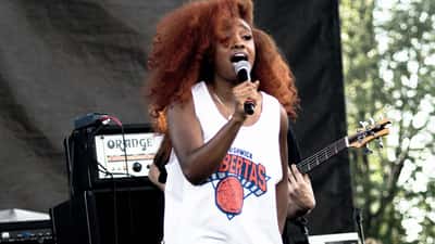 SZA performing on stage at a music festival, vintage-inspired outfit