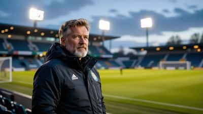 Fotballtrener alene på sidelinjen ved et tomt stadion i skumringen