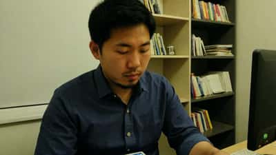 Jeune homme asiatique étudiant avec des flashcards et un ordinateur portable à son bureau à Montréal