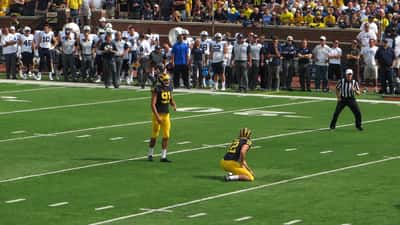 College football placekicker preparing for a field goal attempt at Michigan Stadium