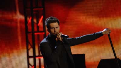 Adam Levine cantando no palco durante show do Maroon 5, técnico vencedor do The Voice