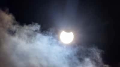 Partielle Sonnenfinsternis mit Wolken über dem Horizont