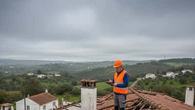 Técnico de construção a inspecionar danos na cobertura de uma casa portuguesa após o Ciclone Kristin em Leiria