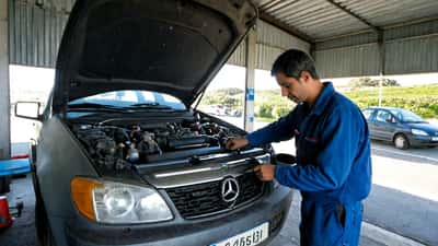 Mecânico português a inspecionar motor diesel numa oficina em Lisboa