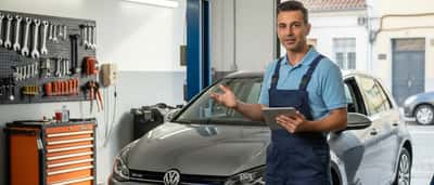 Mecânico português a analisar dados de diagnóstico junto a um carro elevado numa oficina em Lisboa