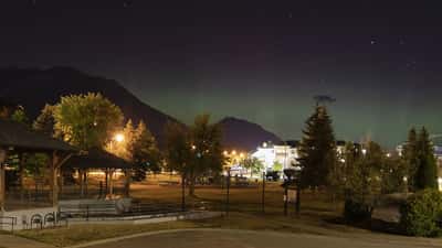 Aurora borealis glowing green and purple above the rooftops of downtown Fernie, British Columbia, Canada at night