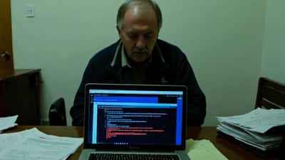 Homme inquiet devant un écran d'ordinateur affichant une alerte malware lors d'un streaming illégal