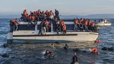 Réfugiés arrivant en canot sur une plage, illustration du droit d'asile international et de la protection des migrants