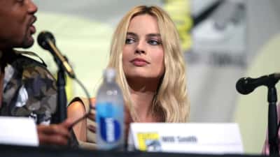 Margot Robbie at public event smiling in formal attire