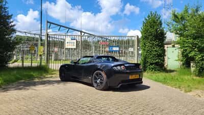 Tesla Roadster de première génération de couleur claire garée sur une route