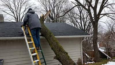 Propriétaire inspectant les dégâts sur le toit de sa maison après une tempête de vent au Québec