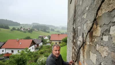 Österreichischer Hausbesitzer untersucht Risse im Fundament nach starken Regenfällen