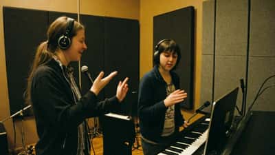 Coach de chant guidant une étudiante dans un studio de musique à Montréal