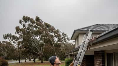 Australian homeowner inspecting gutters and roof before incoming storm in Melbourne suburb