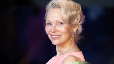 Pamela Anderson souriante, incarnant la beauté naturelle après 50 ans