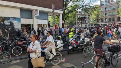 Feestende bezoekers bij Amsterdam Gay Pride festival met kleurrijke vlaggen en muziek