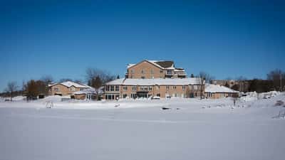 Buildings covered in snow and ice beside a frozen lake in Canada during winter 2026