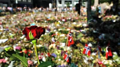 Oslo domkirke med blomster foran fasaden, folkemengde samlet til nasjonal sørgemarsering