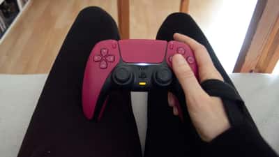 Person holding a PS5 DualSense controller during a gaming session