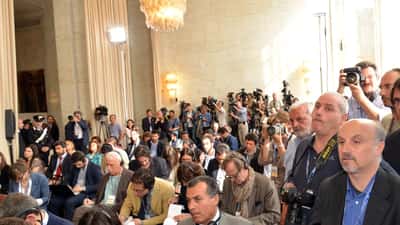 Giornalisti in attesa durante una conferenza stampa con apparecchiature fotografiche e taccuini