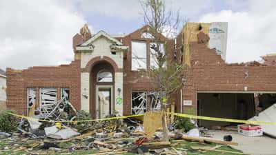 Tornado-damaged home with roof torn off and structural damage visible in Kansas City area