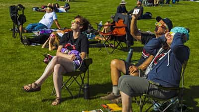 Mensen kijken met eclipsbrillen naar een gedeeltelijke zonsverduistering in een park