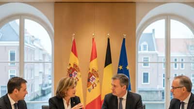 Spaanse en Belgische diplomaten tijdens een vergadering met Europese vlaggen