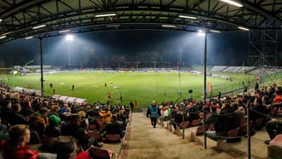 European football stadium at night with floodlights illuminating packed stands
