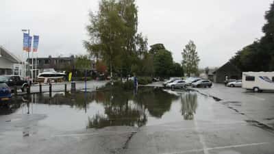 Flooded car park in the UK with cars surrounded by standing water after heavy rain warning