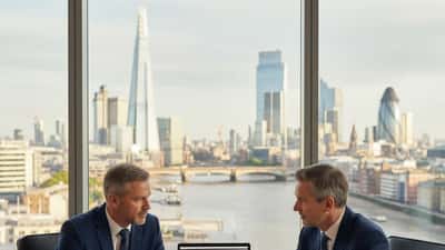 Business professional discussing legal documents with a solicitor in a London City office overlooking the Thames