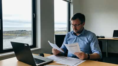 IT-sérfræðingur fer yfir EU AI Act skjöl á skrifborði í Reykjavík skrifstofu