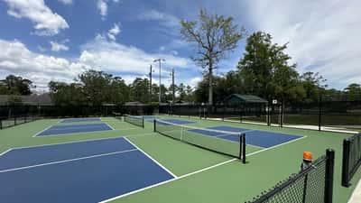 Terrains de pickleball extérieurs au centre sportif, lignes bleues et vertes, zone de cuisine visible