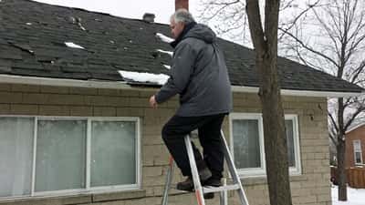 Canadian homeowner inspecting roof damage after a spring snowstorm