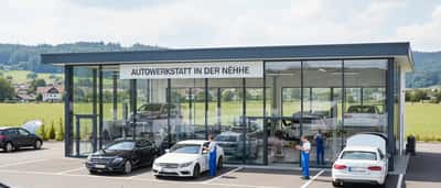 Kfz-Mechaniker inspiziert die Unterseite eines Fahrzeugs auf einer Hebebühne in einer modernen deutschen Autowerkstatt