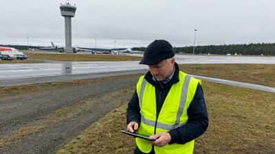 Droneoperatør sjekker tillatelsesapp foran Oslo lufthavn Gardermoen